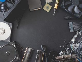 top view of computer parts with harddisk, ram, CPU, graphics card, SSD (solid state drive), motherboard, tools, PSU (Power Supply) and Fan case on black steel background.