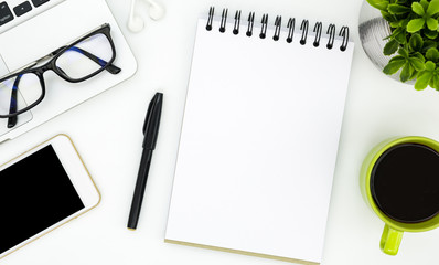 blank notebook page in the middle of white office desk table. top view, flat lay.