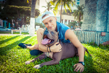 Man and dog american pit bull terrier relaxing at the park embracing and hugging