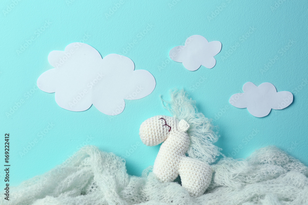 Composition with cute knitted toy horse on color background