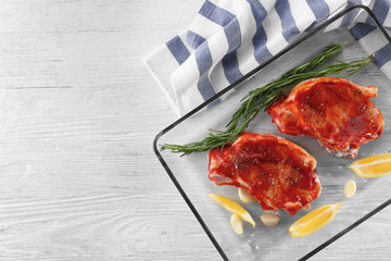 Wall Mural - Pork ribs with tomato sauce and lemon slices in glass baking tray on table