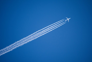 a jet plane flying overhead diagonally with condensation trail.
