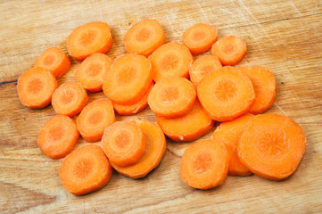 Poster - Fresh carrot slices on wooden chopping board