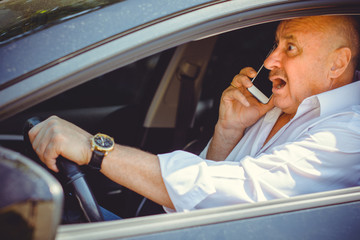 Mature man in car have a trouble. Accident on a road. Senior talk to smartphone in a car