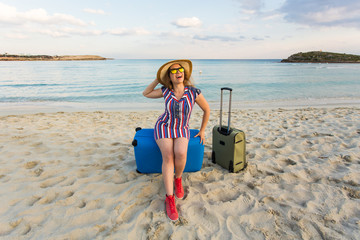 Happy laughing woman tourist with suitcases near the sea. Travel and summer vacation concepts