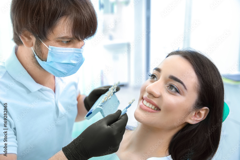 Dentist checking and selecting color of teeth in clinic