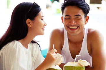 Wall Mural - Couple is having coconut drinks at seaside