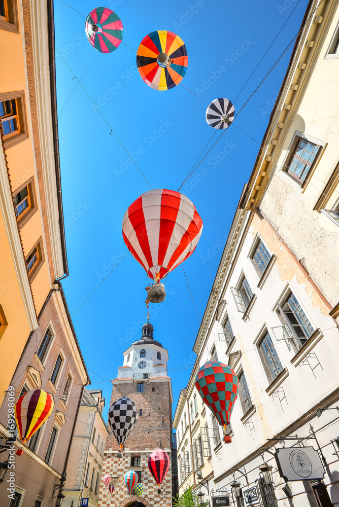 Lublin, Poland - August 10, 2017: Beautiful street and old bright buildings in the old town of Lublin, Poland. View on Cracow gate, Lublin. Mountebanks Carnaval in Lublin old town. - obrazy, fototapety, plakaty 