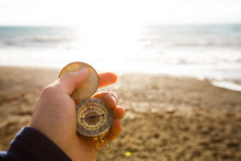 Point Of View Photo Of Man Holding Compass In The Hand On The Sea And Beach Background.