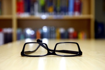 Wall Mural - Pair of eyeglasses on a library table