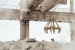 Overhead crane with mechanical multivalve clamshell grab in hot outdoors industrial plant shop. Heavy industry.