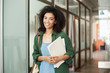 © Cookie Studio - Cheerful african beautiful girl student smiling looking at camera holding books in university. Education concept.