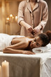 © Cookie Studio - Tender african girl relaxing enjoying healthy spa massage with oil.