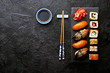 Variation of sushi and rolls on stone table. Sushi rolls, sashimi set with chopsticks. Top view with copy space.