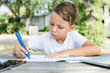 © click_and_photo - Little boy doing homework in garden