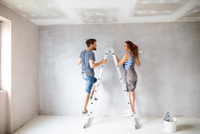 Young Couple Painting Walls In Their New House.