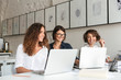 © Drobot Dean - Three young happy women working by the table