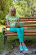 © anko_ter - Young girl resting on a bench with a laptop in the park on a sunny day