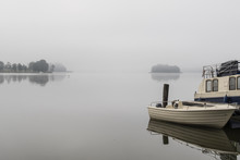 Boat Rests On The Shore Of A Lake On A Foggy Morning