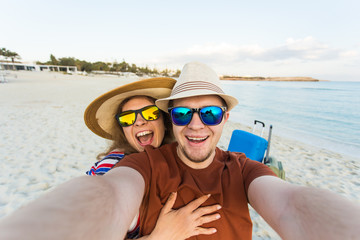 Wall Mural - Happy young couple in love takes selfie portrait on the beach in Cyprus. Pretty tourists make funny photos for travel blog in Europe.