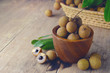 Fresh longan fruit with peel the skin show white meat and black seed on a wooden background.