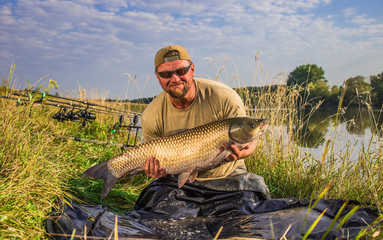 Happy angler with carp fishing trophy.Amur (grass carp).Fish trophy