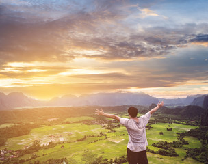 Wall Mural - a man raising hand up on mountain peak, in sunrise, traveling in vang vieng in laos