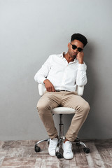 Poster - Tired afro american man in sunglasses sitting in a chair