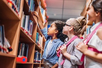 schoolgirls looking for books in library