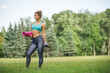 © Iulia - Young beautiful woman in sportswear. She's holding a training mat. Going to do sports training, gymnastics. Outdoors summer