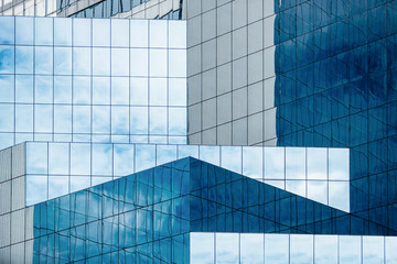 blue sky and clouds reflecting in windows of modern office building