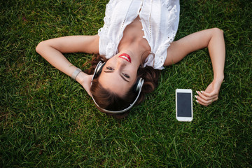 Canvas Print - Happy young woman lies on grass outdoors.