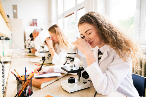 Cuadros en Lienzo Beautiful high school students with microscopes in laboratory.