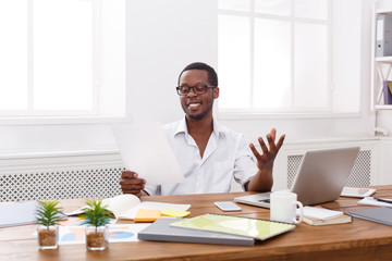 Young black businessman read documents in modern white office