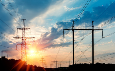 Wall Mural - power transmission tower silhouetted against the sunset glow.