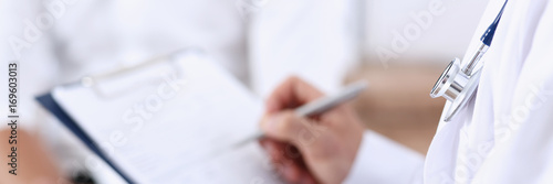 Fotografie, Obraz Male doctor hand hold silver pen filling patient history list