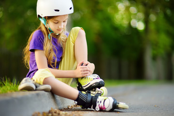 Wall Mural - Pretty little girl learning to roller skate on beautiful summer day in a park