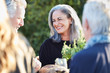 © Trinette Reed/Stocksy - Portrait of senior woman with group of friends enjoying a Farm To Table Dinner Party in backyard