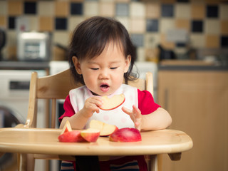 Wall Mural - baby girl eating apple  at home