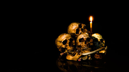 Wall Mural - The visual art still life image of human skulls and pile bone with candle Light