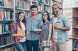 Classmate, international friendship, communication, education and teenage concept. Group of cheerful students in casual outfits with note books, devices are studying in the library