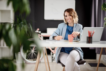 Businesswoman in early thirties working at home while sitting in personal work space 