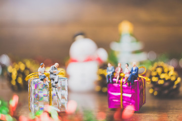 Miniature people on gift box with Christmas Day celebration background