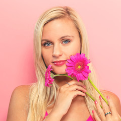 Wall Mural - Young woman with flowers on a pink background