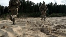 Military Soldiers With Weapons Running On Sand Back View. Military Man