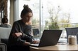 © Wavebreak Media - Young woman using laptop while sitting on armchair