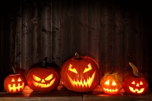 Group Of Halloween Jack O Lanterns At Night With A Rustic Dark Wooden Background