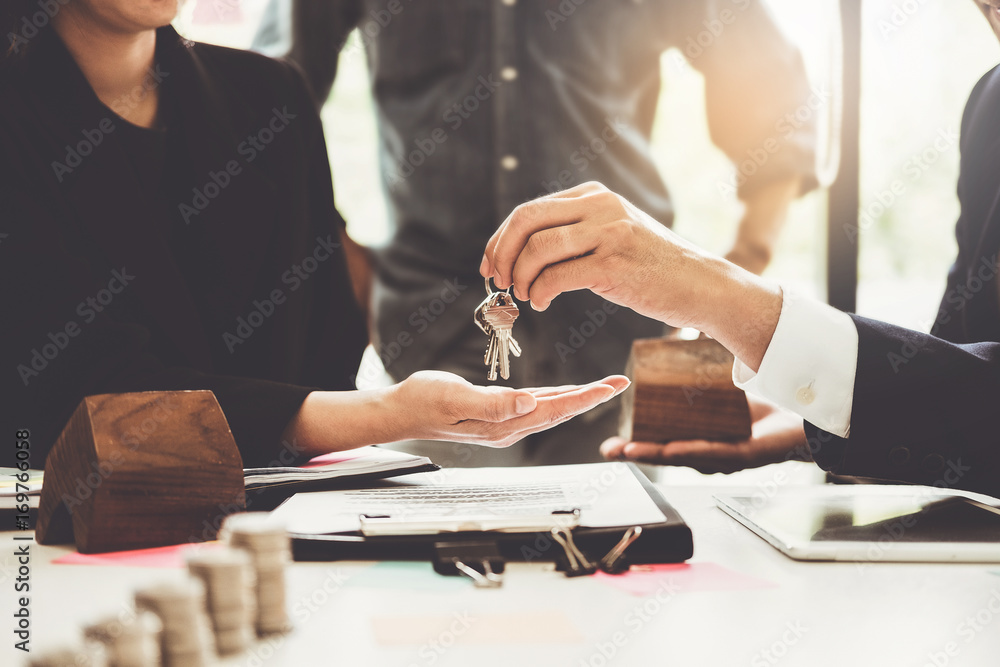 Agents are giving house keys of customer and holding dollar us bank at agency office. Agreement and real estate concept. - obrazy, fototapety, plakaty 