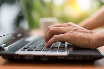 male hands on keyboarding while working messaging  via social networks using computer laptop. background of nature