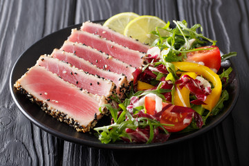 Wall Mural - beautiful food: steak tuna in sesame, lime and fresh salad close-up on a plate on the table. horizontal